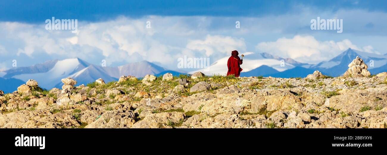 Atemberaubendes Panorama des Tibetischen Hochlandes mit schneebedeckten Bergen. Pilger mit roter Robe im Vordergrund. Stockfoto
