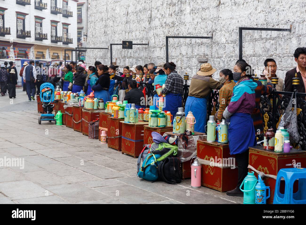 Pilger warten in der Schlange am Eingang des Jokhang-Tempels. Wichtiger Ort des tibetischen buddhismus. Frauen servieren heiße Getränke für die Gläubigen. Stockfoto