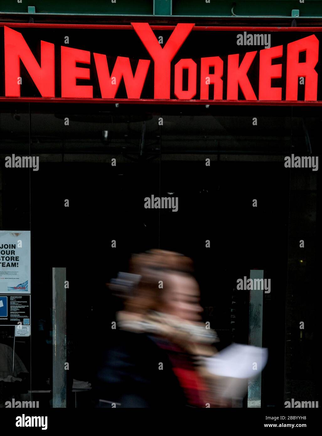 Hamburg, Deutschland. April 2020. Eine Frau spaziert vor dem geschlossenen Eingang eines Kaufhauses der Modekette Newyorker in der Hamburger Innenstadt. Kredit: Axel Heimken / dpa / Alamy Live News Stockfoto