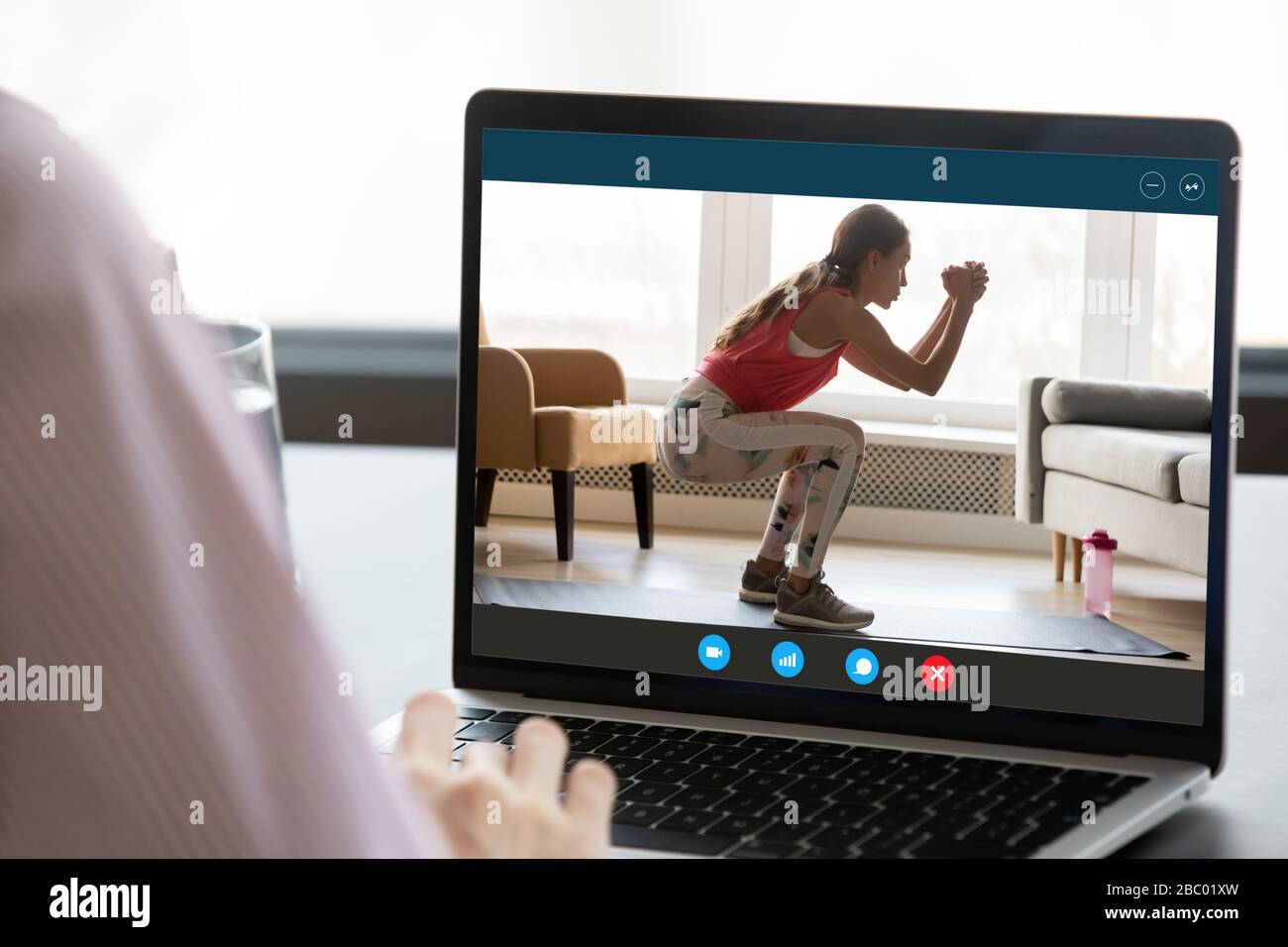 Junge Frau beobachtet Online-Trainingstraining auf dem Laptop Stockfoto