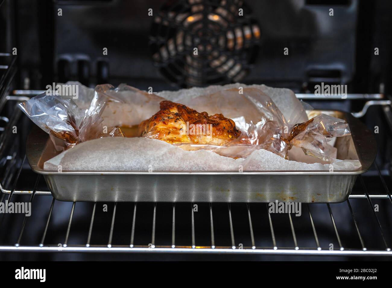 Das Fleisch mit Gewürzen wird im Ofen auf einer Metallbohrung in einer Muffe gebacken. Stockfoto