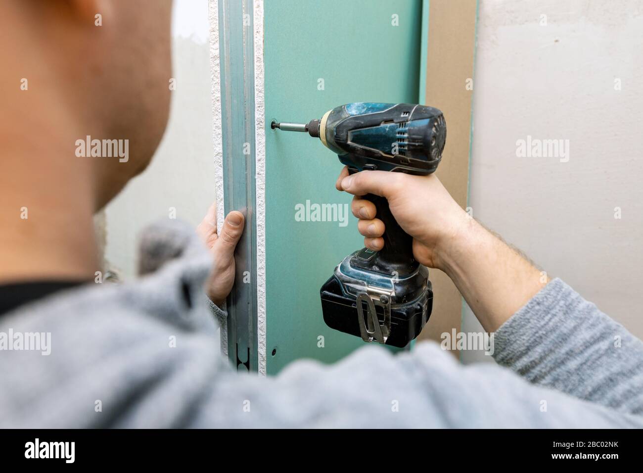 Mann, der feuchtigkeitsbeständige Trockenwandplatten für die Badezimmerschwand installiert Stockfoto