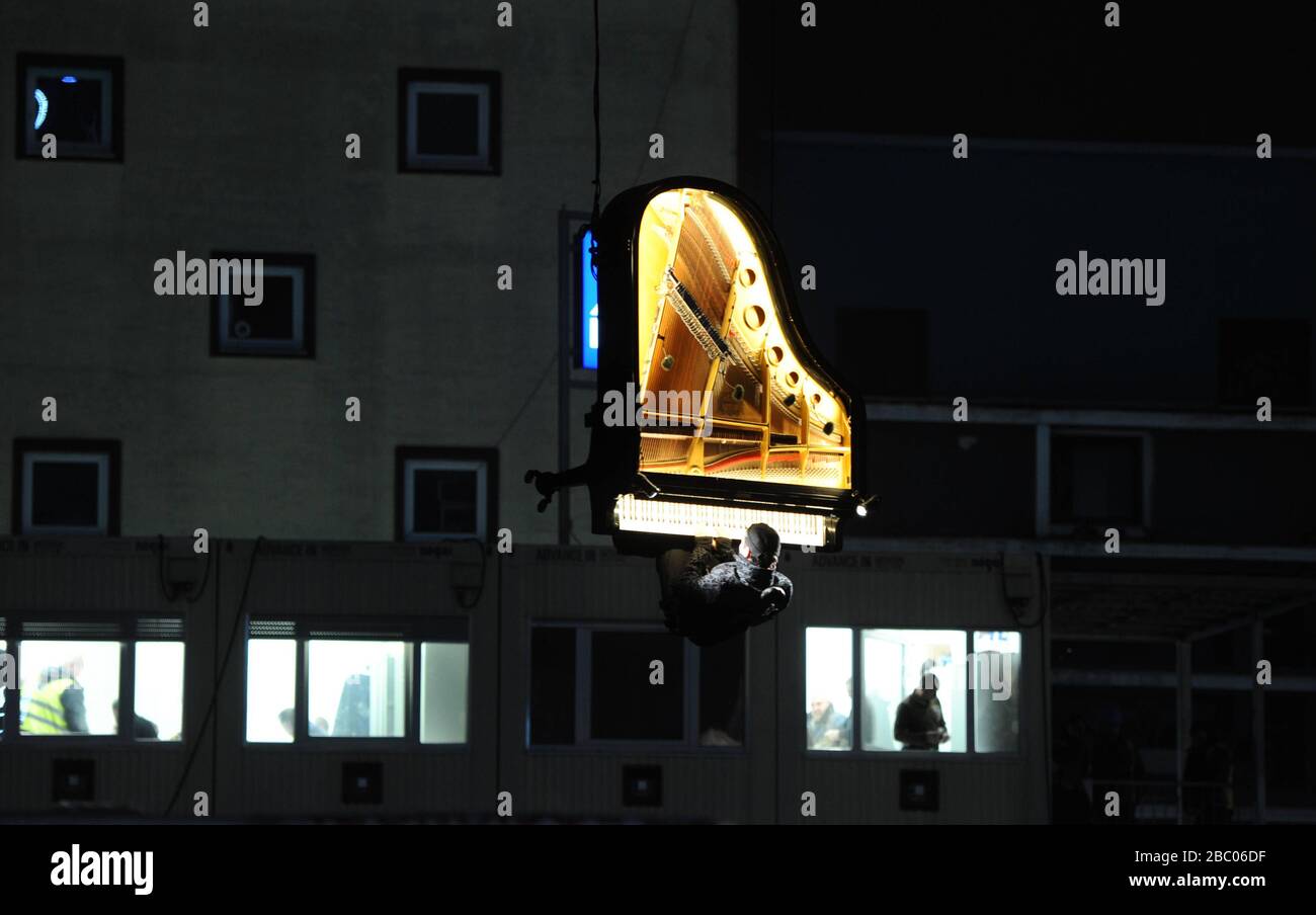 "Piano Vertical" von Alain Roche: Um 6:45 Uhr am Morgen gibt der an einem Kran hängende Pianist Alain Roche ein Konzert im Werksviertel oberhalb der Baustelle des neuen Konzertsaals. [Automatisierte Übersetzung] Stockfoto