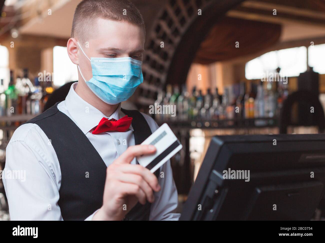 Der Kellner arbeitet in einem Restaurant in einer medizinischen Maske Stockfoto