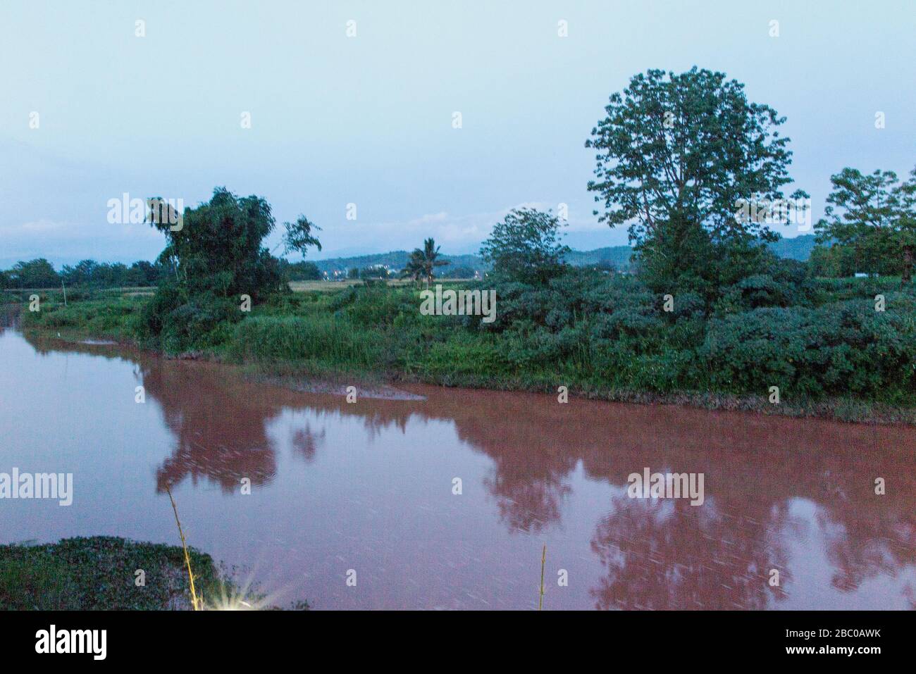 Es hat in den Bergen geregnet. Das Wasser des Flusses ist rot, weil der rote Boden ins Wasser fließt. Stockfoto