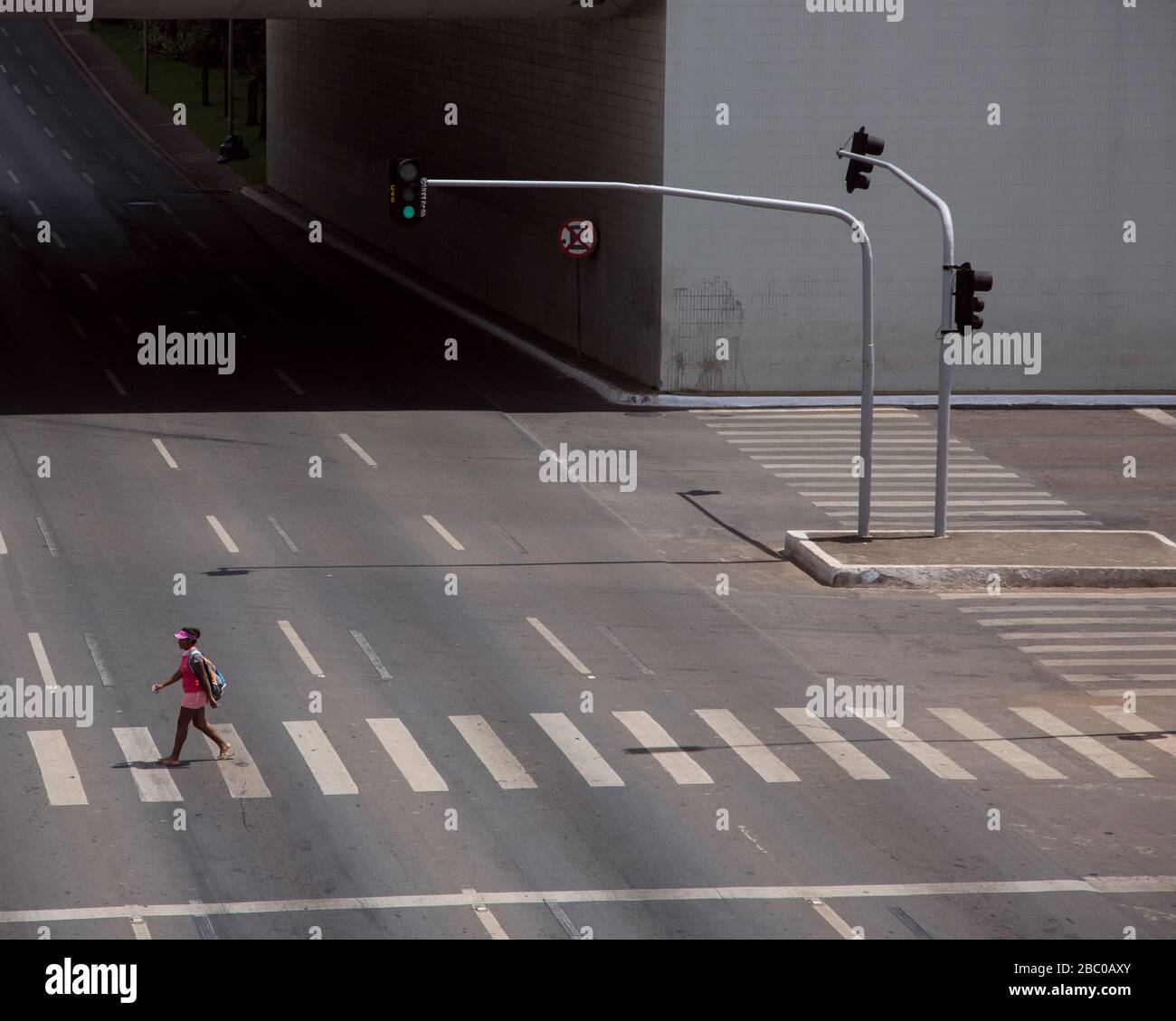 Ein weiter Blick als einsamer Fußgänger führt über die Straße in Brasilia, der Hauptstadt Brasiliens. Stockfoto