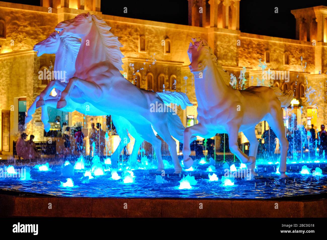 Nachtaufnahme von Pferdeplastiken im Brunnen im Global Village, Dubai, VAE. Stockfoto