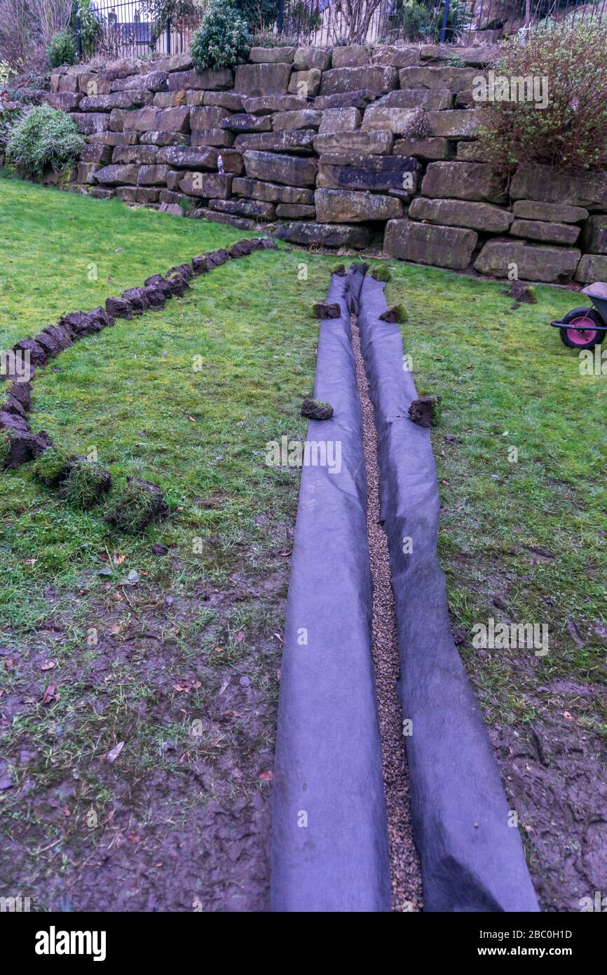 Installation eines Ablaufgrabens in einem Gartenrasen, Stockfoto