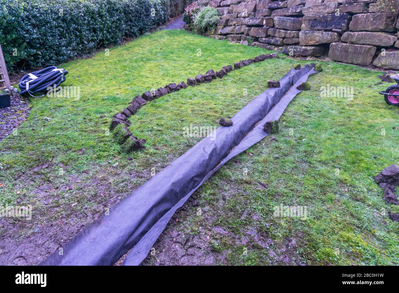 Installation eines Ablaufgrabens in einem Gartenrasen, Stockfoto