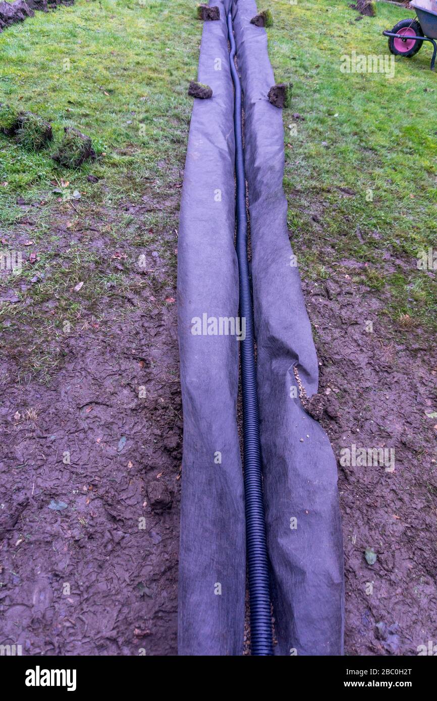 Installation eines Ablaufgrabens in einem Gartenrasen, Stockfoto