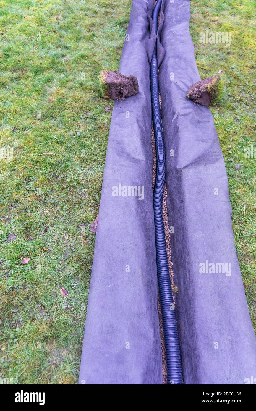 Installation eines Ablaufgrabens in einem Gartenrasen, Stockfoto