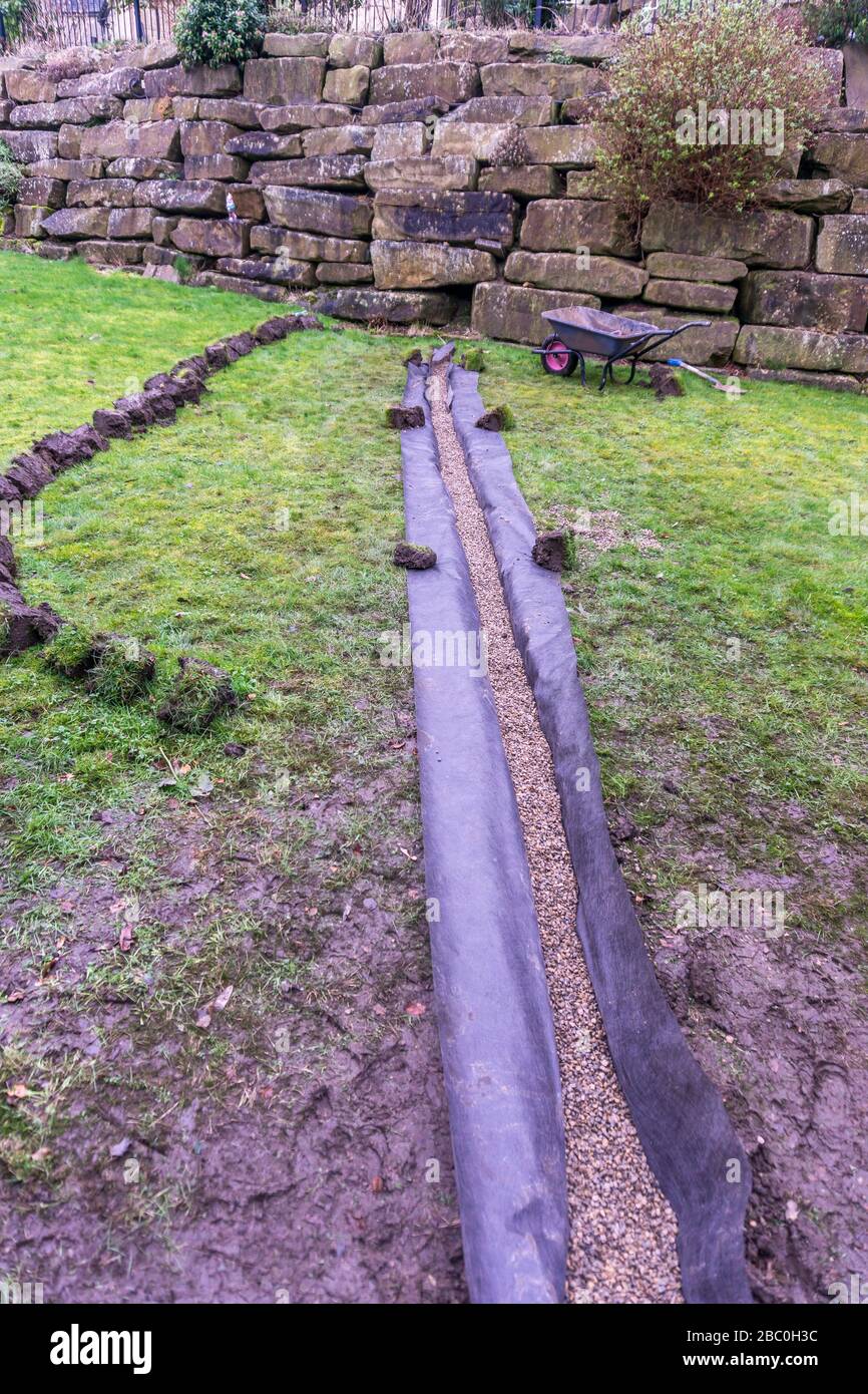 Installation eines Ablaufgrabens in einem Gartenrasen, Stockfoto