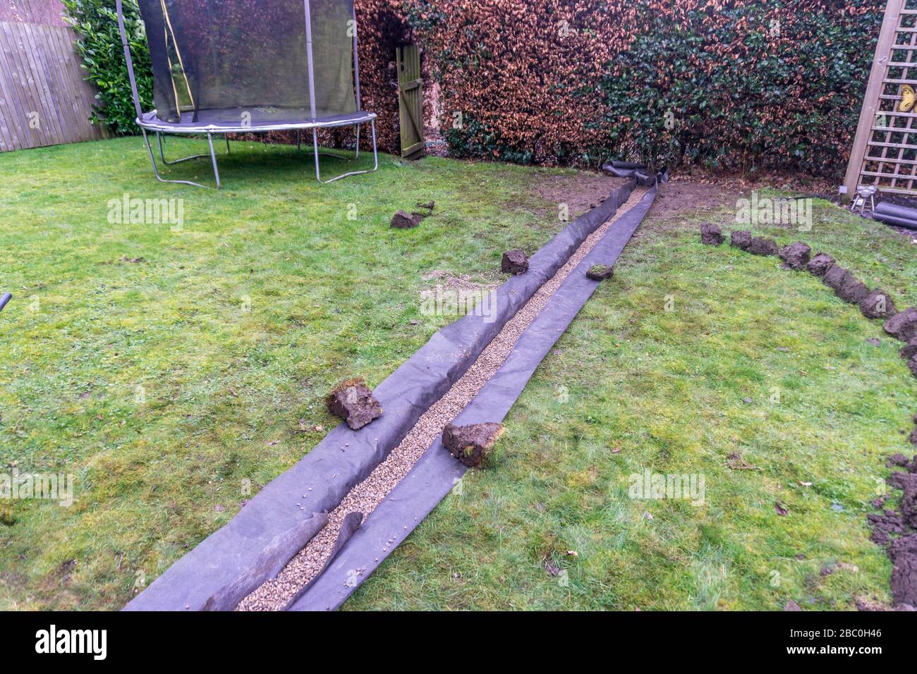 Installation eines Ablaufgrabens in einem Gartenrasen, Stockfoto