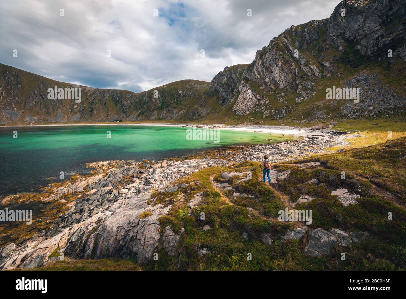 WANDERER, DIE SICH DEM STRAND VON HOYVIKA NÄHERN, WEISSER SAND UND TÜRKISFARBENES WASSER UMGEBEN VON BERGEN, STAVE, ANDOYA, NORWEGEN Stockfoto