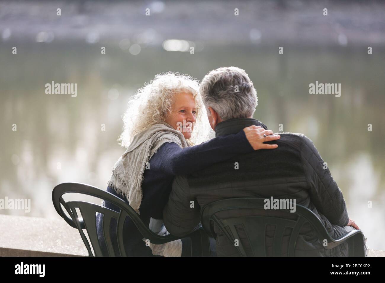 Liebevoll aktives Senioren-Paar umarmt am Parkteich Stockfoto