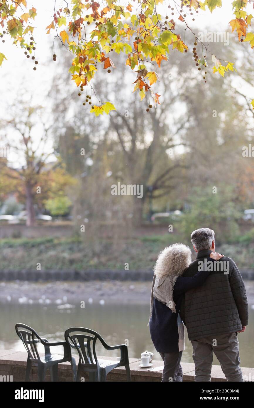Liebevoll aktives Senioren-Paar am Herbstparkteich Stockfoto