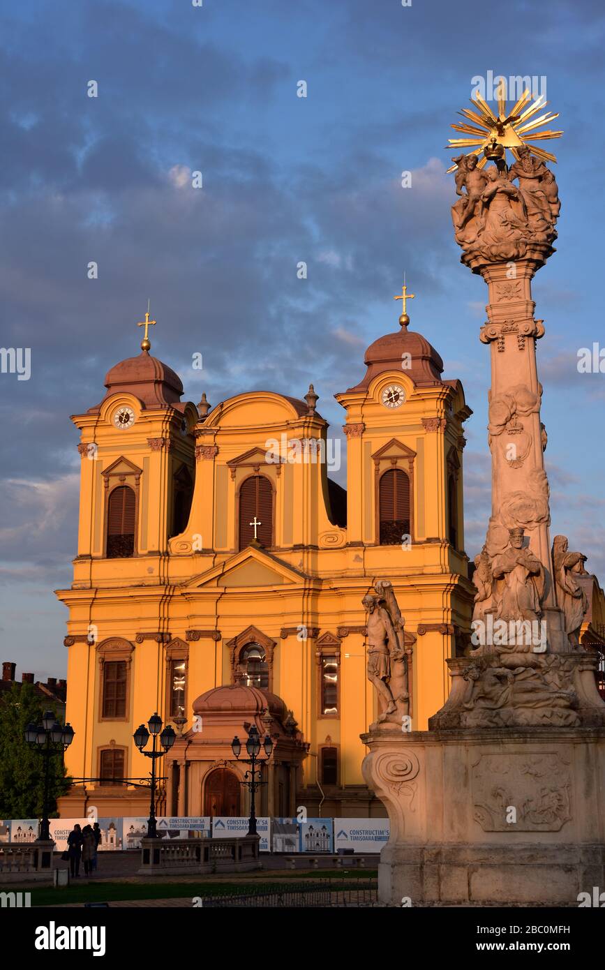 Rumänien, Timis, Timisoara, katholische Kathedrale und Säule der Heiligen Dreifaltigkeit (Monumett zur Plage) auf Piata Uniri bei Sonnenuntergang, Altstadt. Stockfoto