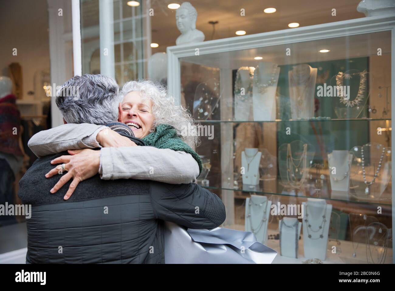 Senioren-Paar umarmt, Schaufensterbummel im Juweliergeschäft Stockfoto