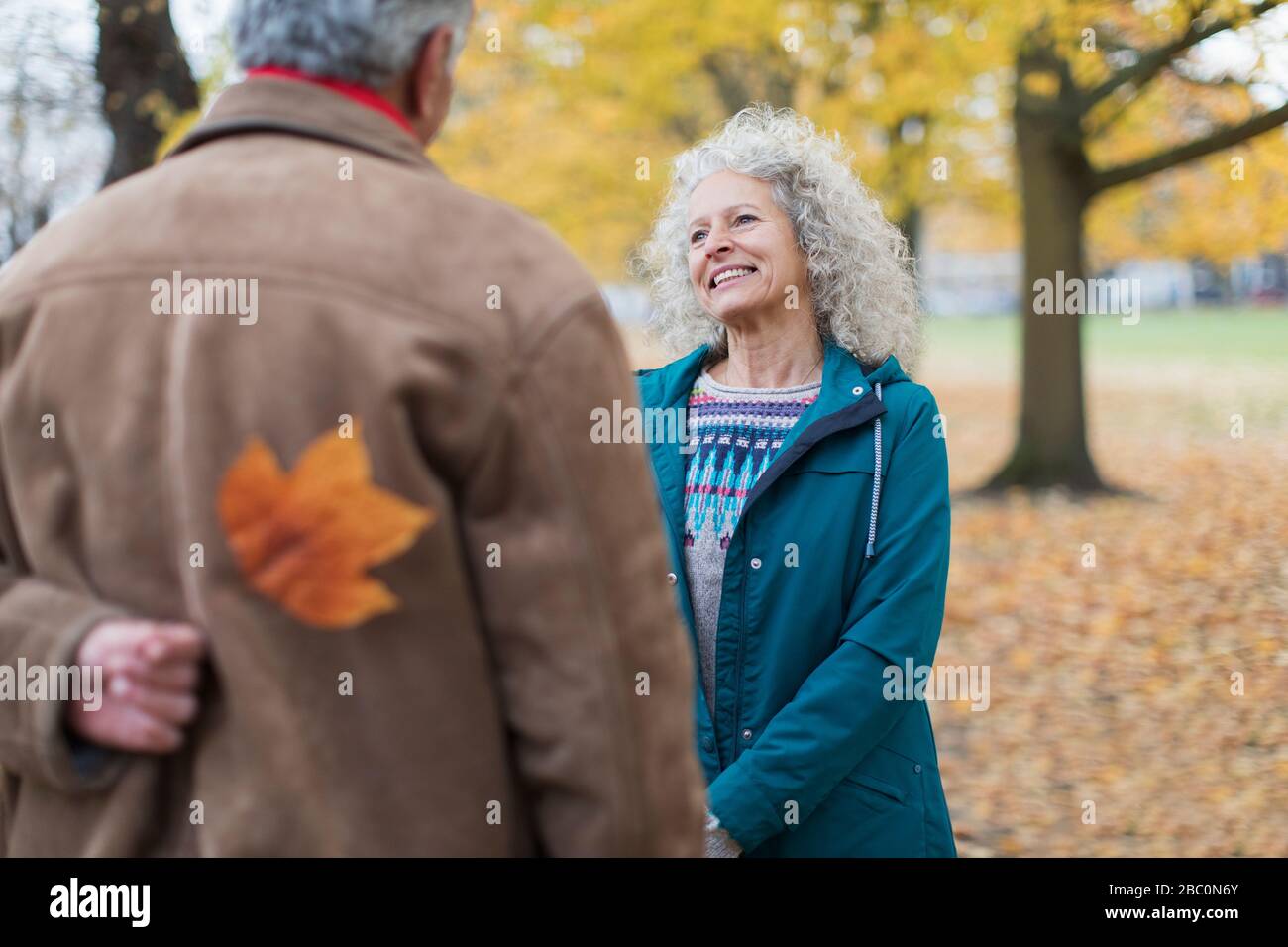 Verspielter Senioren-Ehemann überraschende Frau mit Herbstblatt im Park Stockfoto