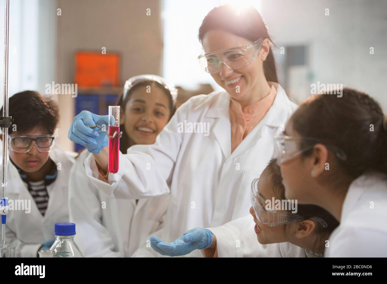 Lächelnde Chemielehrerin und Studenten, die wissenschaftliche Experimente im Laborunterricht durchführen Stockfoto