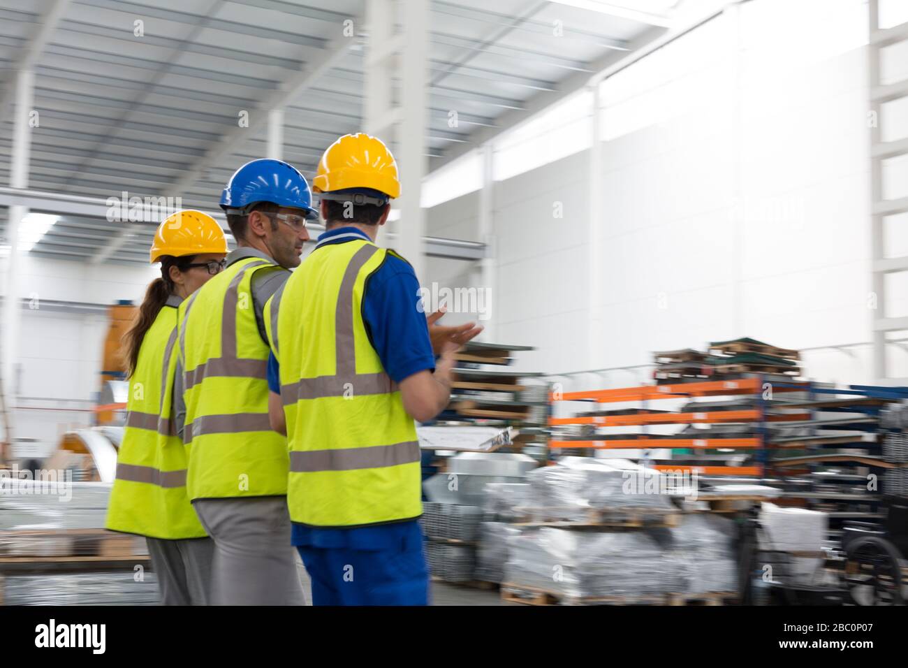 Vorgesetzter und Mitarbeiter, die im Lager spazieren gehen und sprechen Stockfoto