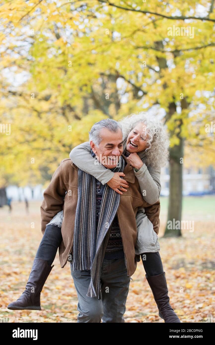 Verspieltes Senioren-Paar piggybacking im Herbstpark Stockfoto
