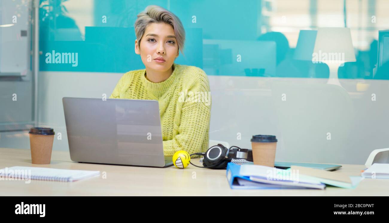 Portrait selbstbewusste, entschlossene junge Geschäftsfrau, die am Laptop arbeitet Stockfoto