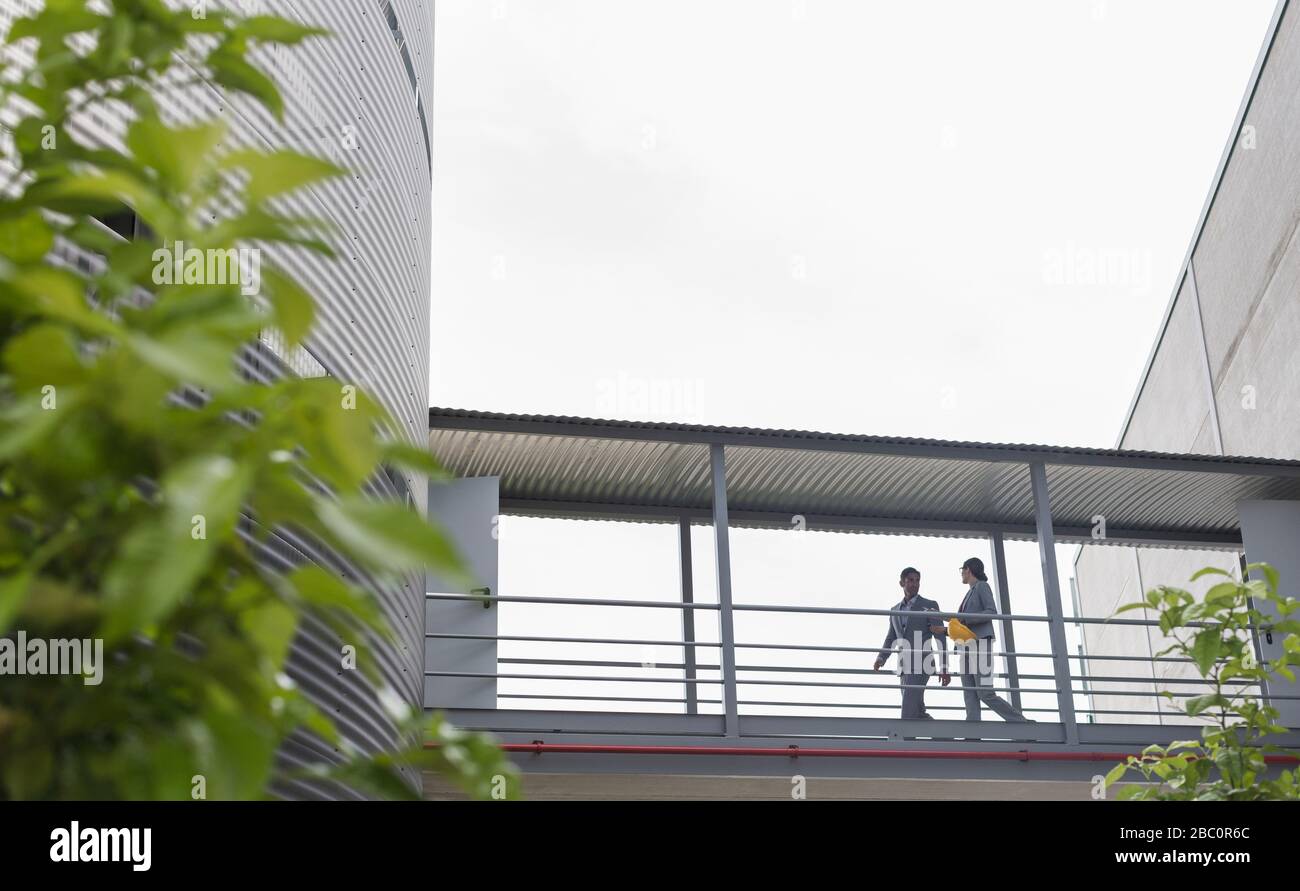 Aufsichtsplätze, die auf einem erhöhten Gehweg zwischen den Fabrikgebäuden laufen Stockfoto