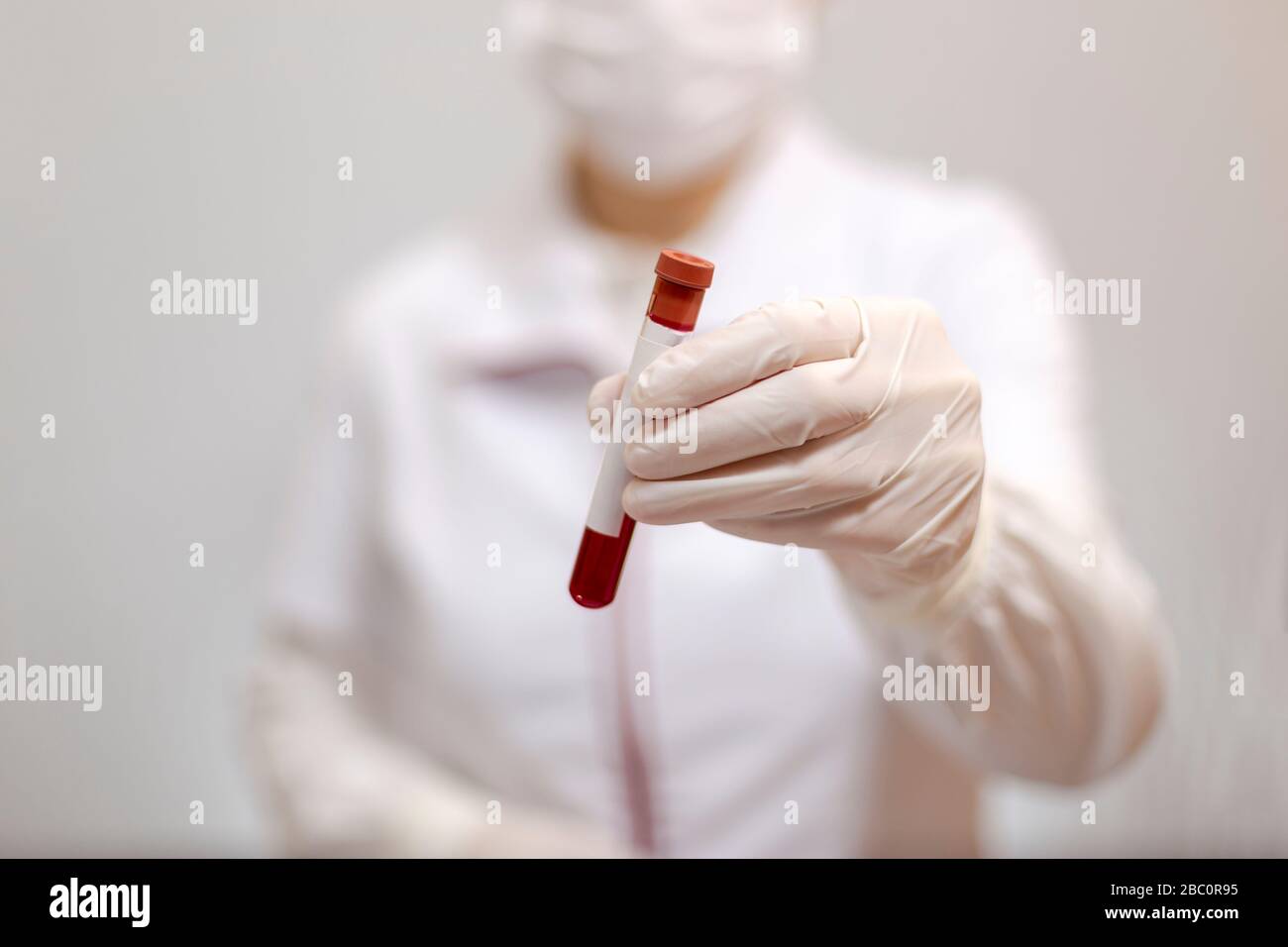 Arzt mit Maske und Handschuhen, der ein Rohr mit medizinischer Analyse, Blut und Textstelle enthält Stockfoto