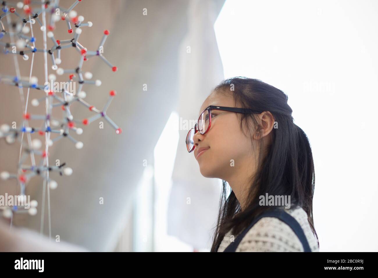 Nachdenkliche, neugierige Schülerin, die die Molekularstruktur untersucht Stockfoto