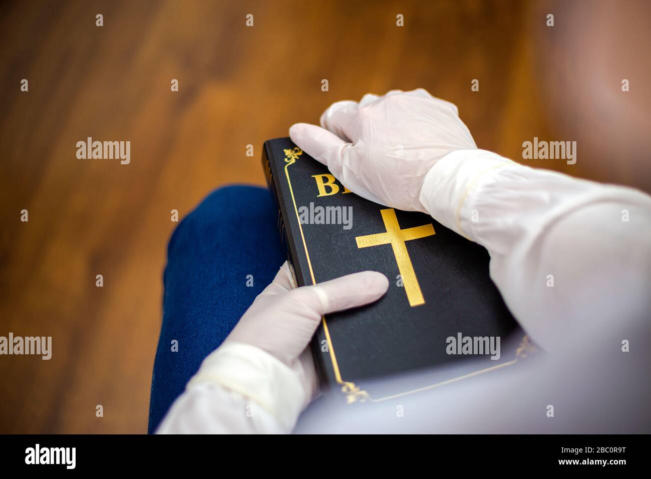 Person, Krankenschwester oder Arzt mit Maske und Handschuhen stehen im Gebet mit der Bibel in der Hand. Der Infizierte steht im Gebet mit der Bibel in der Hand Stockfoto
