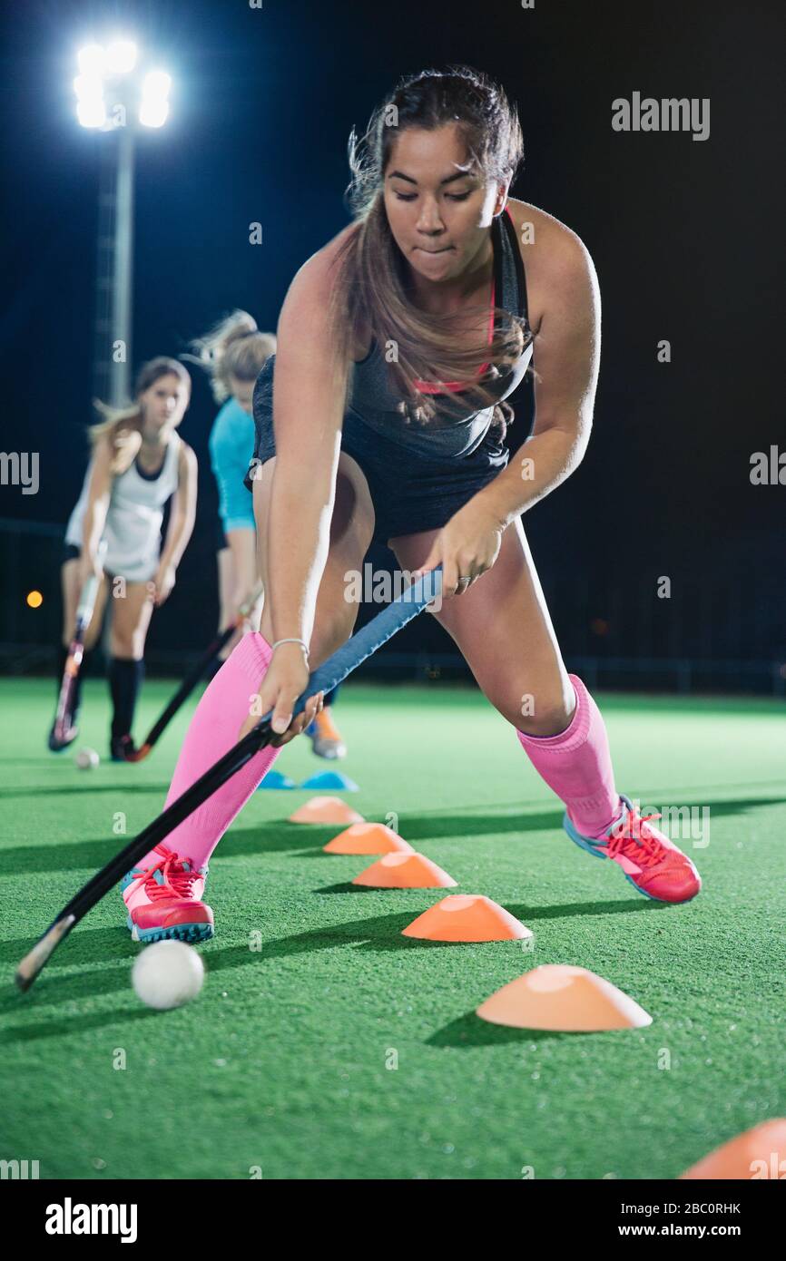 Konzentrierter junger Hockeyspieler, der Sportübung auf dem Feld übt Stockfoto