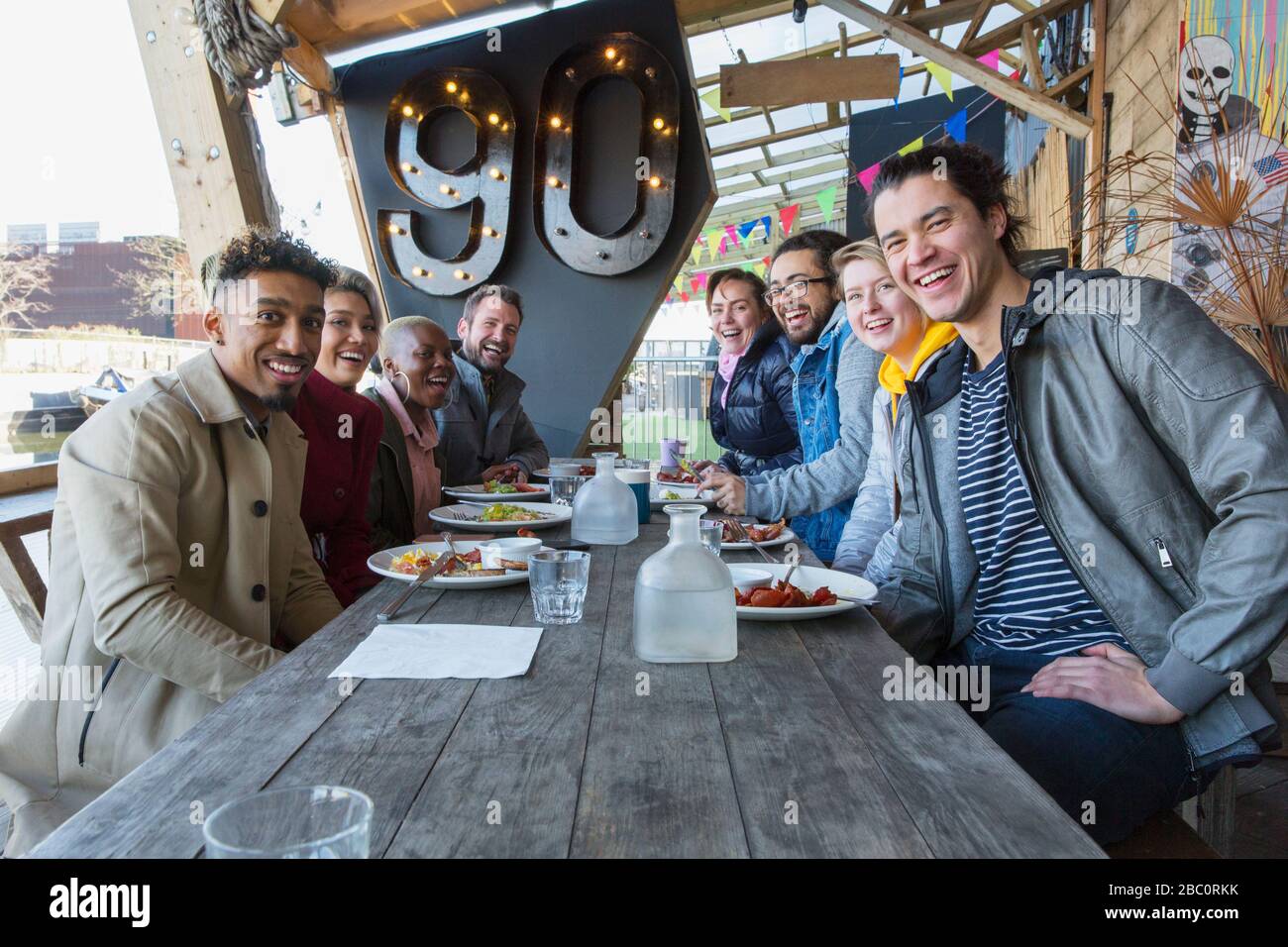 Portrait lächelnde Freunde, die auf der Außenterrasse des Restaurants essen Stockfoto