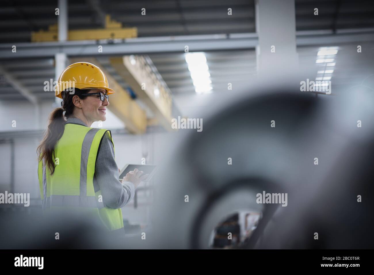 Selbstbewusste Arbeiterinnen, die digitale Tabletts in der Stahlfabrik verwenden Stockfoto