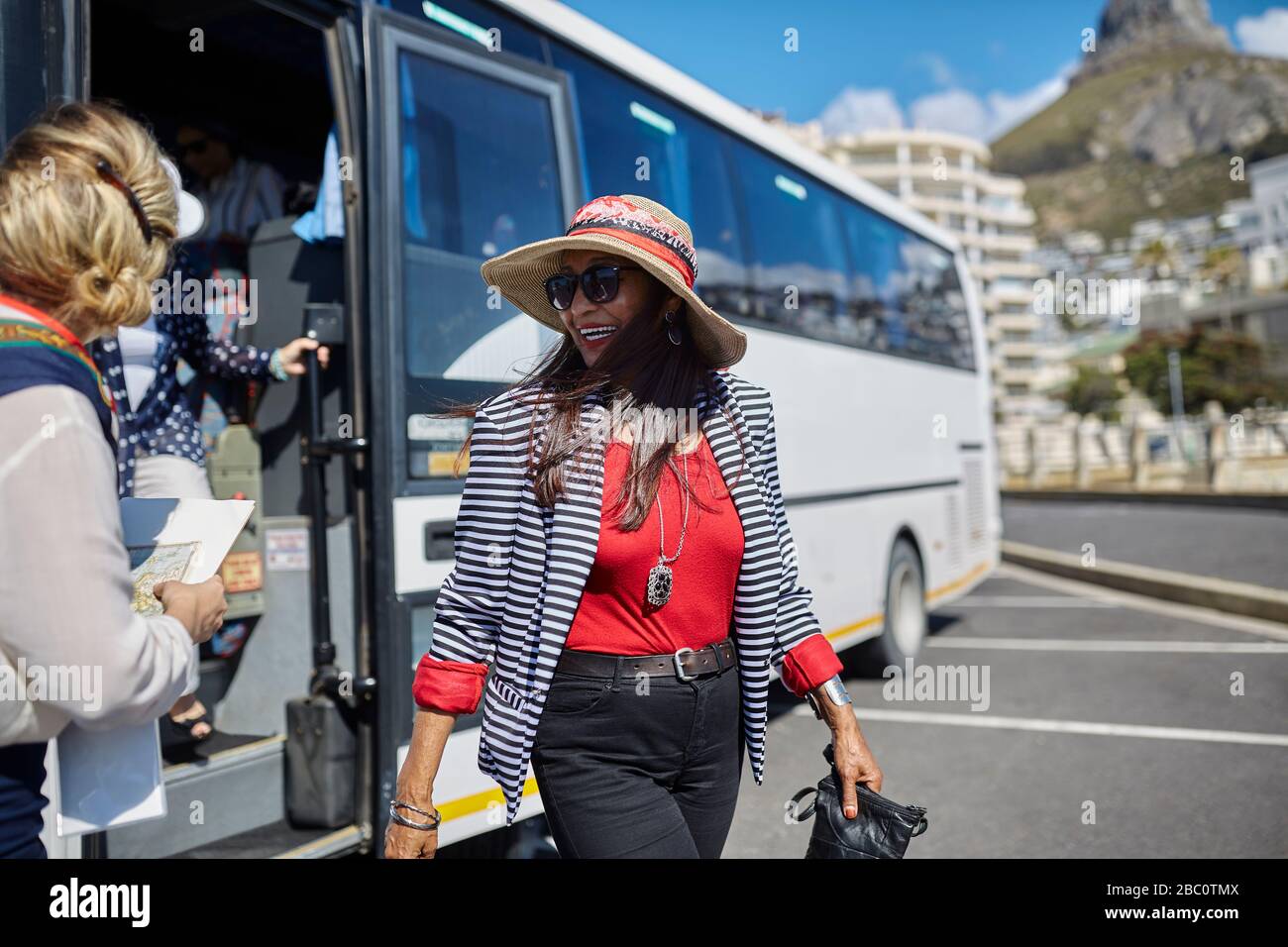 Lächelnde aktive Seniorin Tourist, die vom Reisebus abkommt Stockfoto