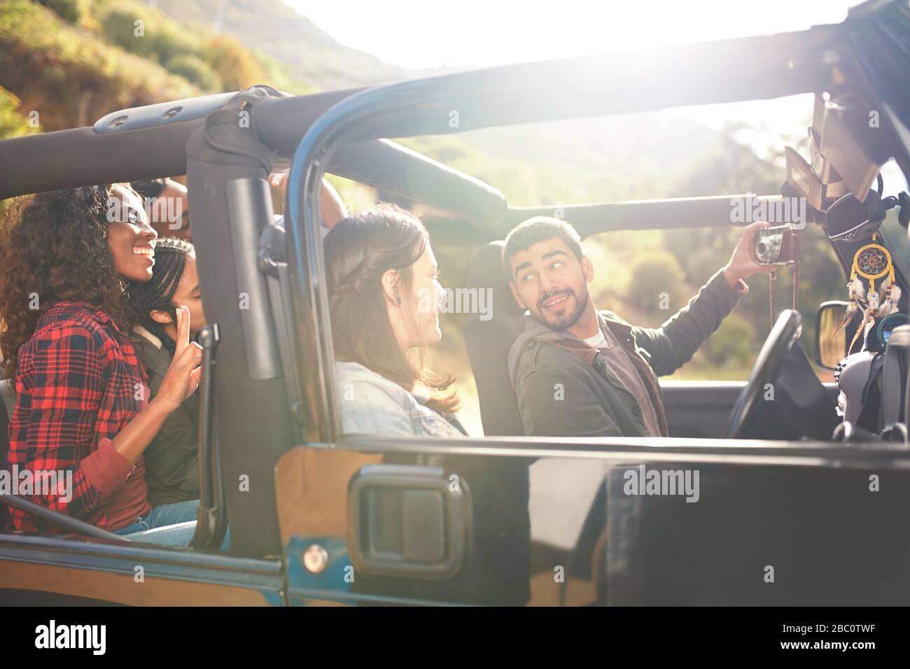 Mann mit Digitalkamera, der selfie mit Freunden in Jeep nimmt Stockfoto