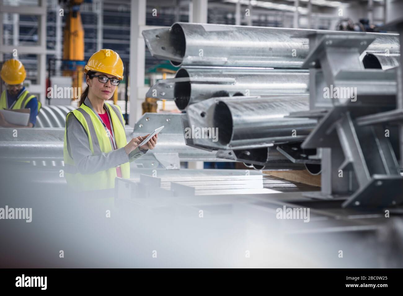 Portrait selbstbewusste Arbeiterinnen mit digitalem Tablet in Stahlfabrik Stockfoto