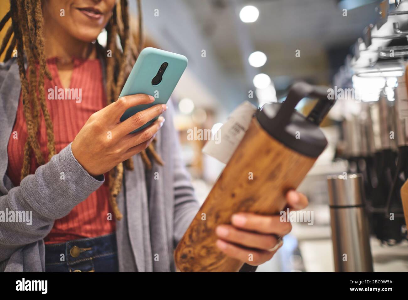 Frau mit Smartphone fotografiert isolierte Flasche im Laden Stockfoto