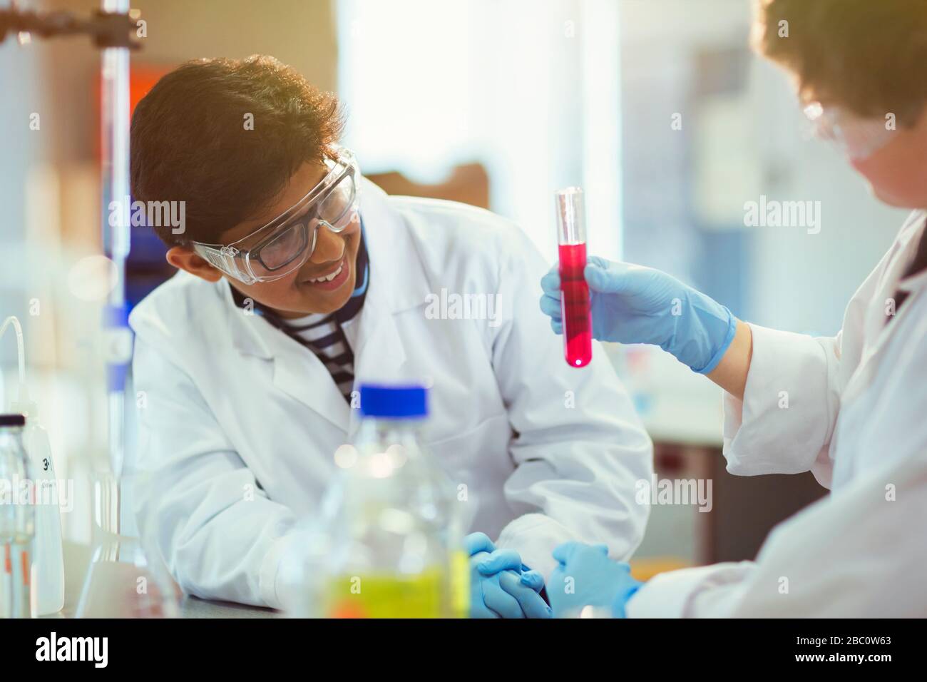 Junge Studenten untersuchen Flüssigkeit im Reagenzglas und führen wissenschaftliche Experimente im Laborunterricht durch Stockfoto