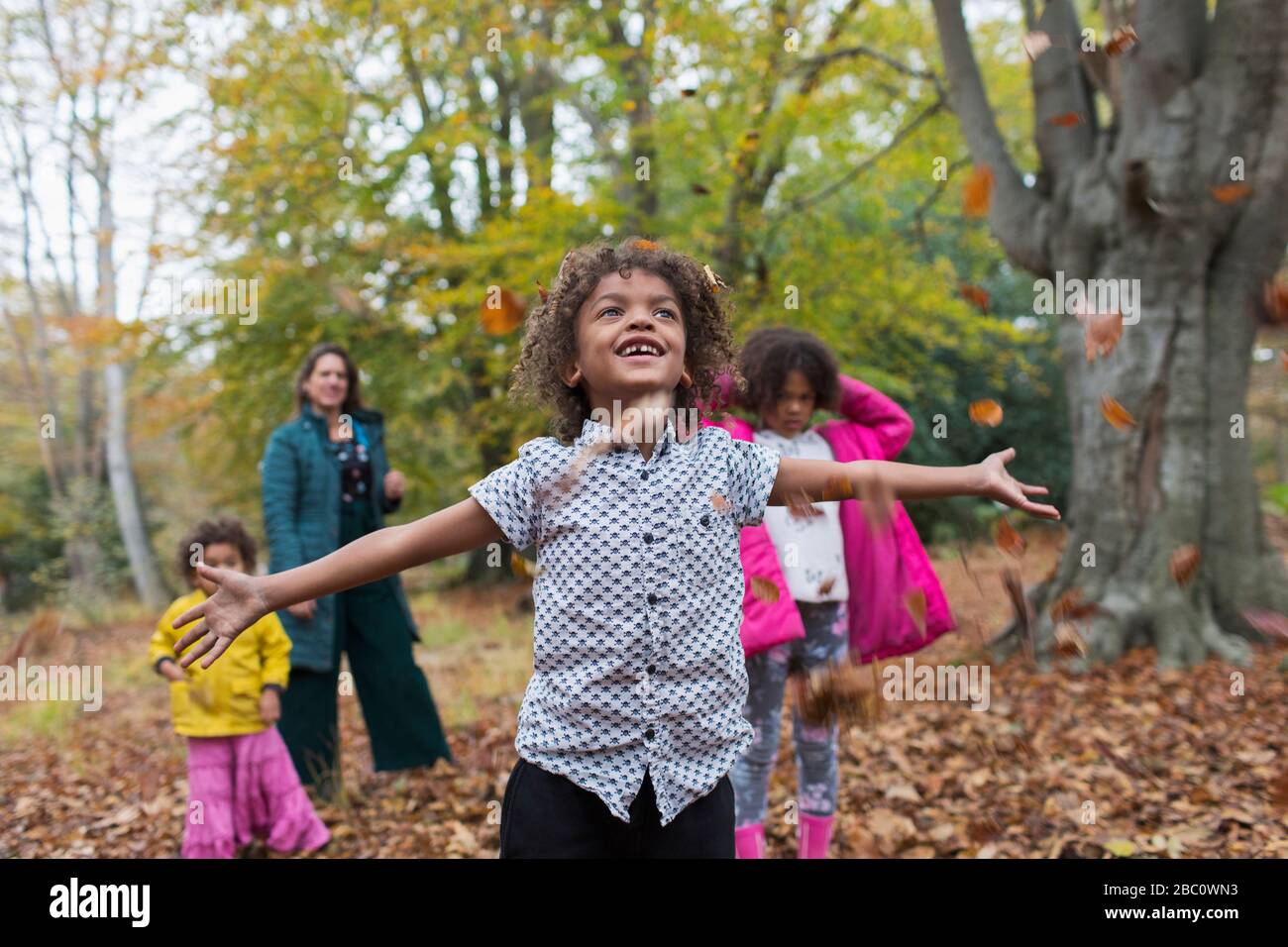 Unbeschwerter Junge, der im Herbst mit der Familie im Wald spielt Stockfoto