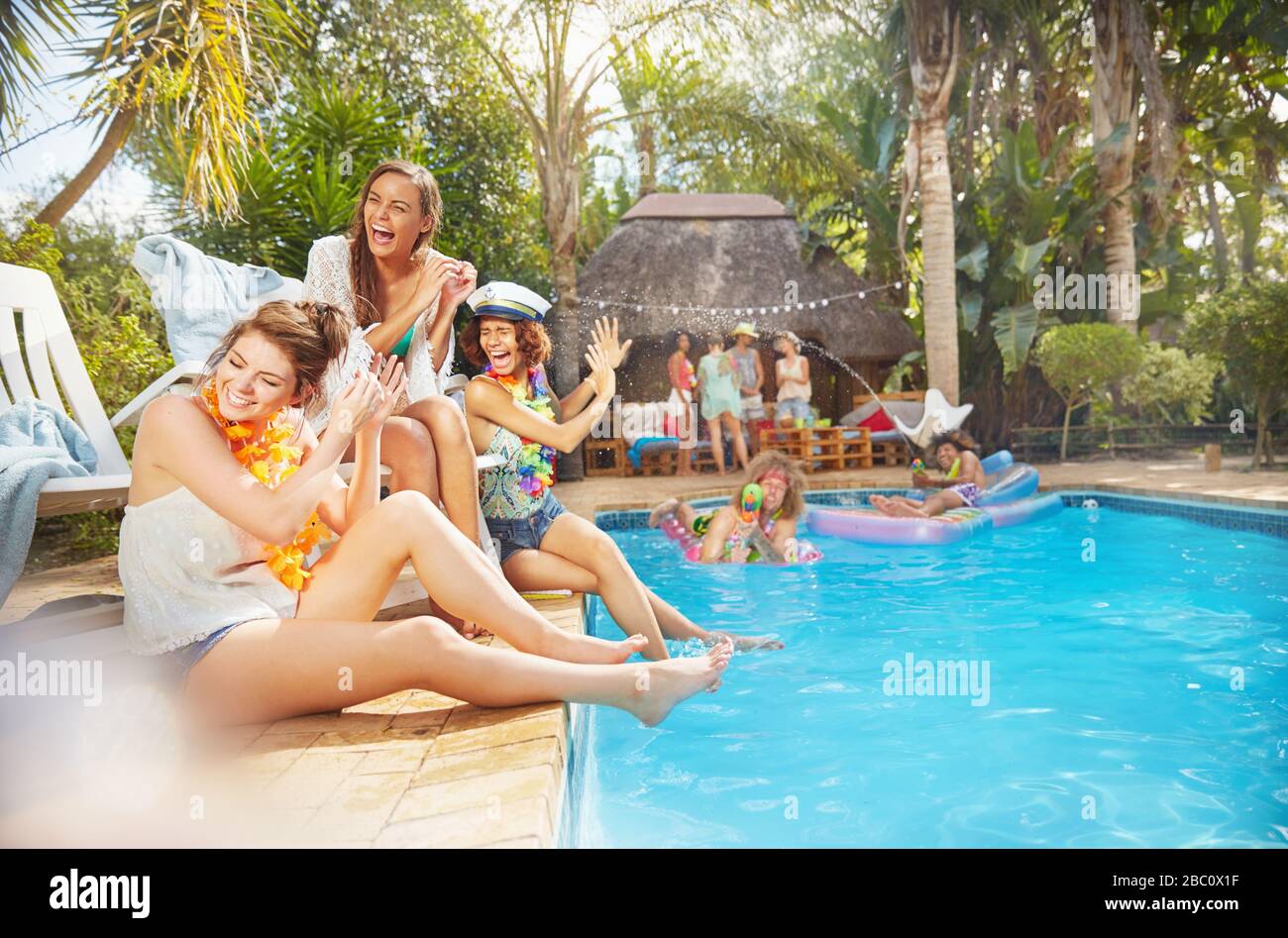 Junge Freunde lachen und spritzen im sonnigen Sommer am Pool Stockfoto