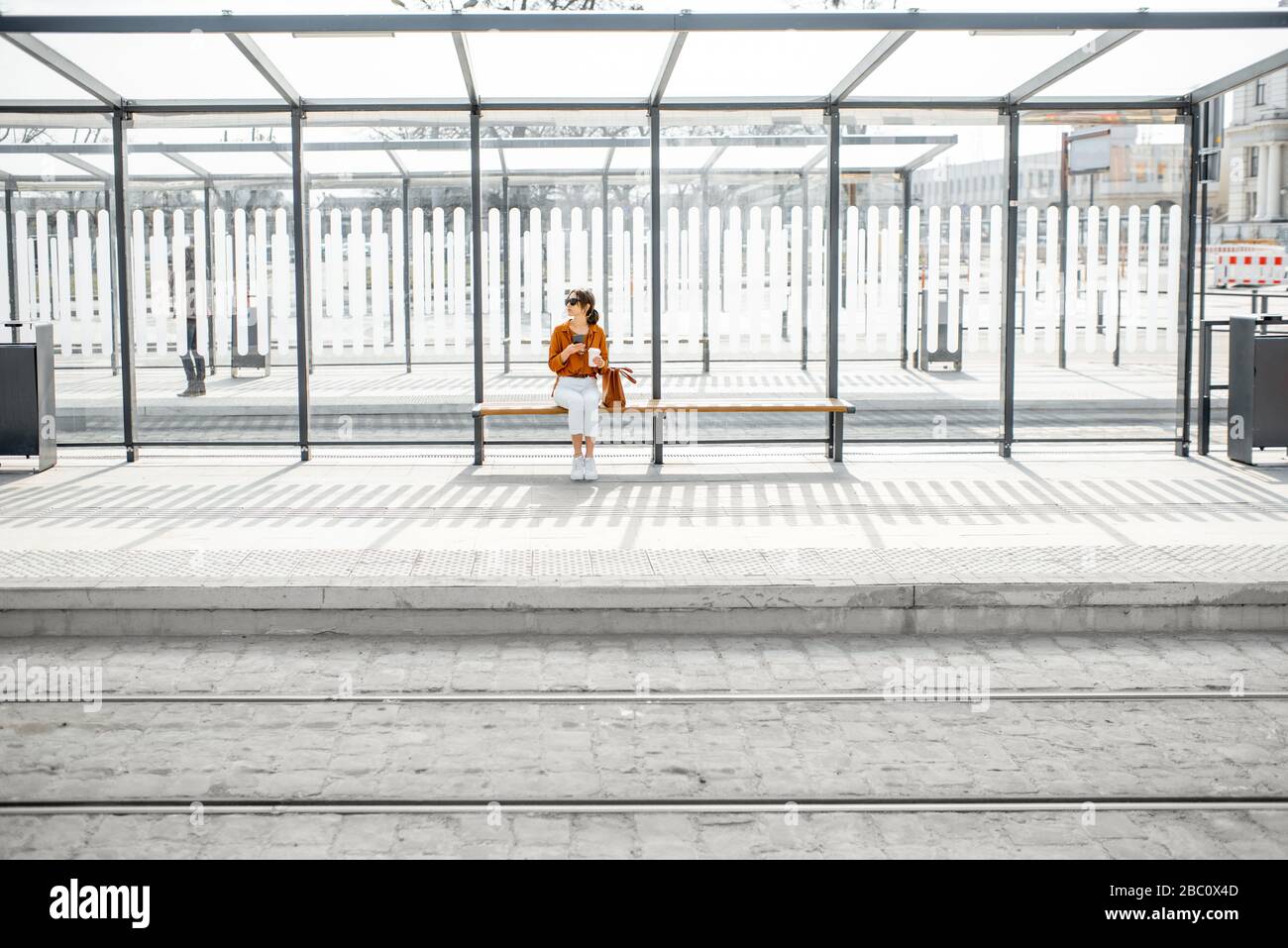 Allein sitzende Frau an einem sonnigen Tag im Freien, Plan für einen modernen Stopp. Konzept eines Verkehrs- und Stadtlebens Stockfoto