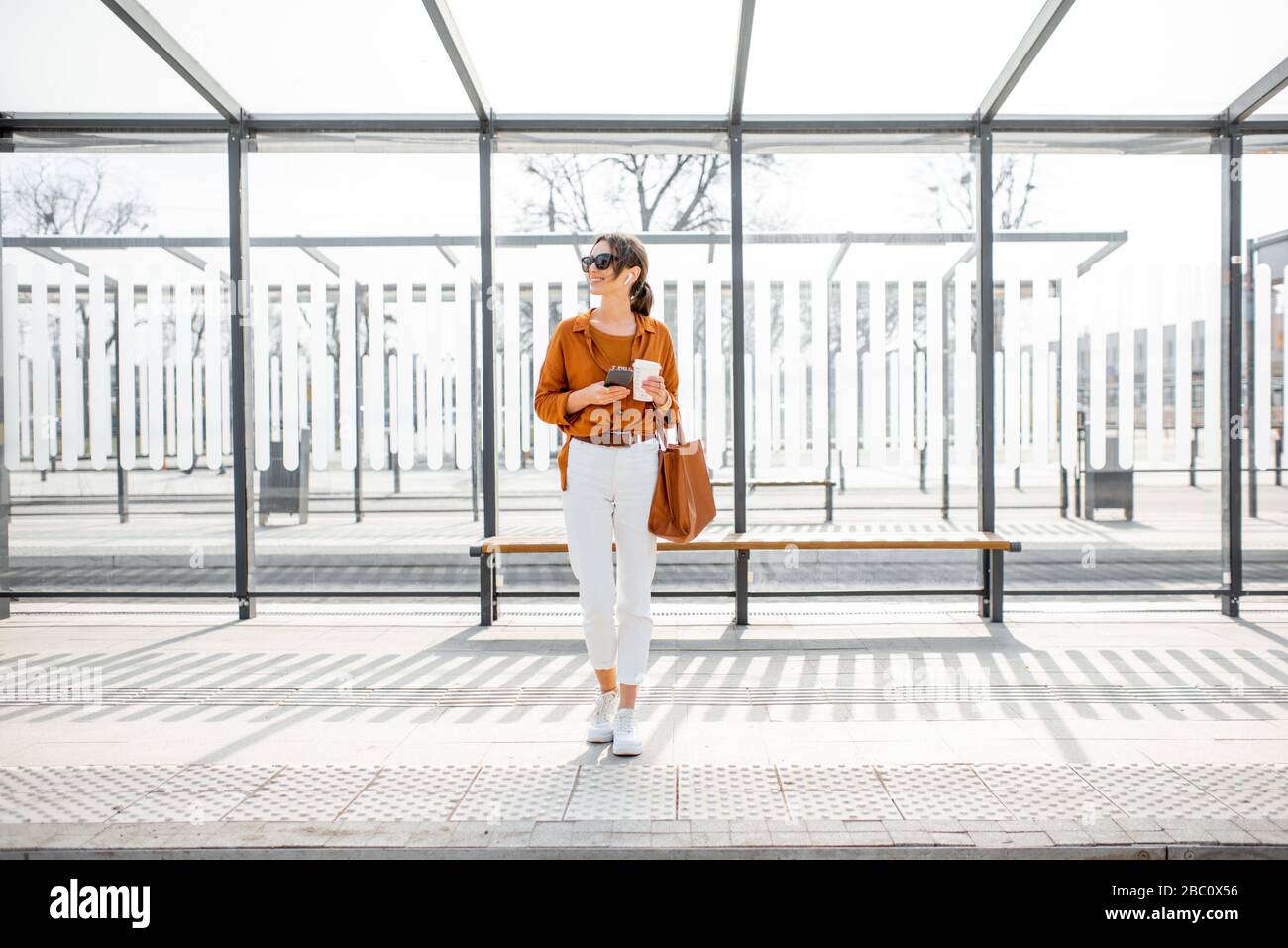 Allein stehende Frau an einem sonnigen Tag im Freien hält an öffentlichen Verkehrsmitteln. Konzept eines Verkehrs- und Stadtlebens Stockfoto