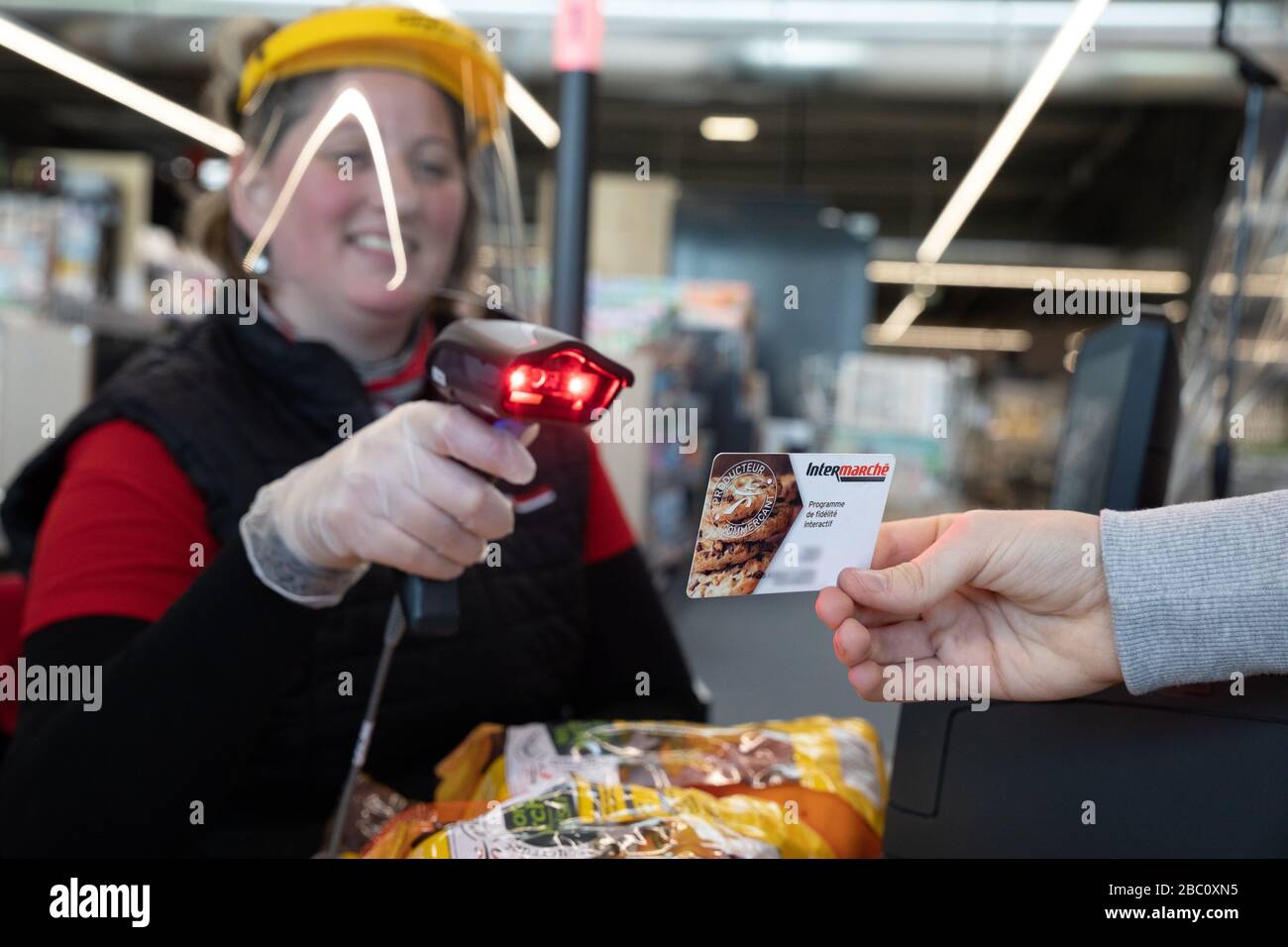 KASSIERER IN EINEM INTERMARCHE-SUPERMARKT MIT GESICHTSMASKE UND HANDSCHUHEN, VORBEUGENDE GESUNDHEITSMASSNAHME FÜR DIE CORONAVIRUS EPIDEMIE, RUGLES, NORMANDIE, FRANKREICH Stockfoto