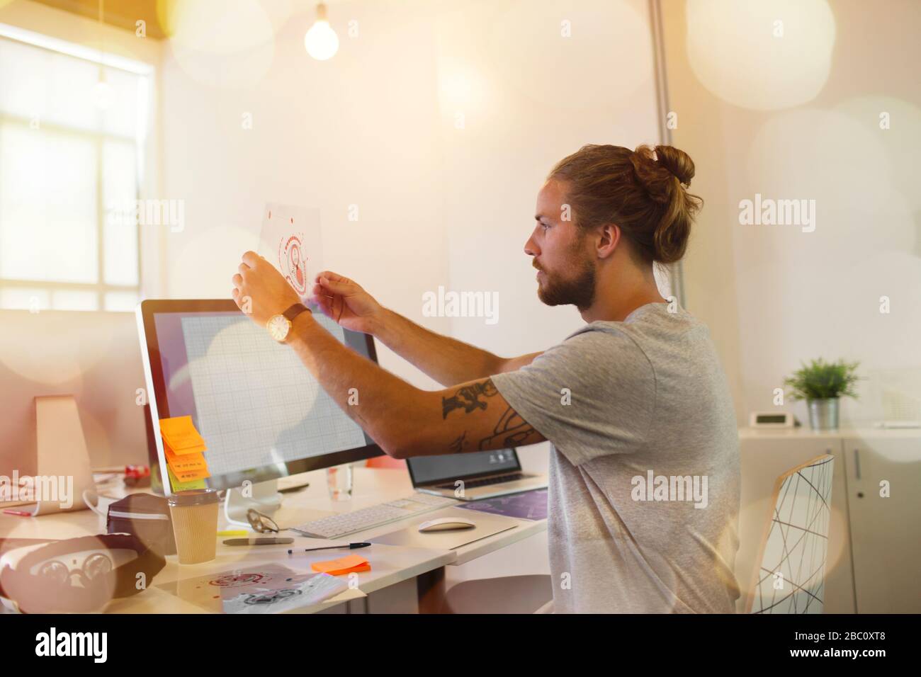 Männlicher Designer untersucht Transparenzdiagramm im Büro Stockfoto