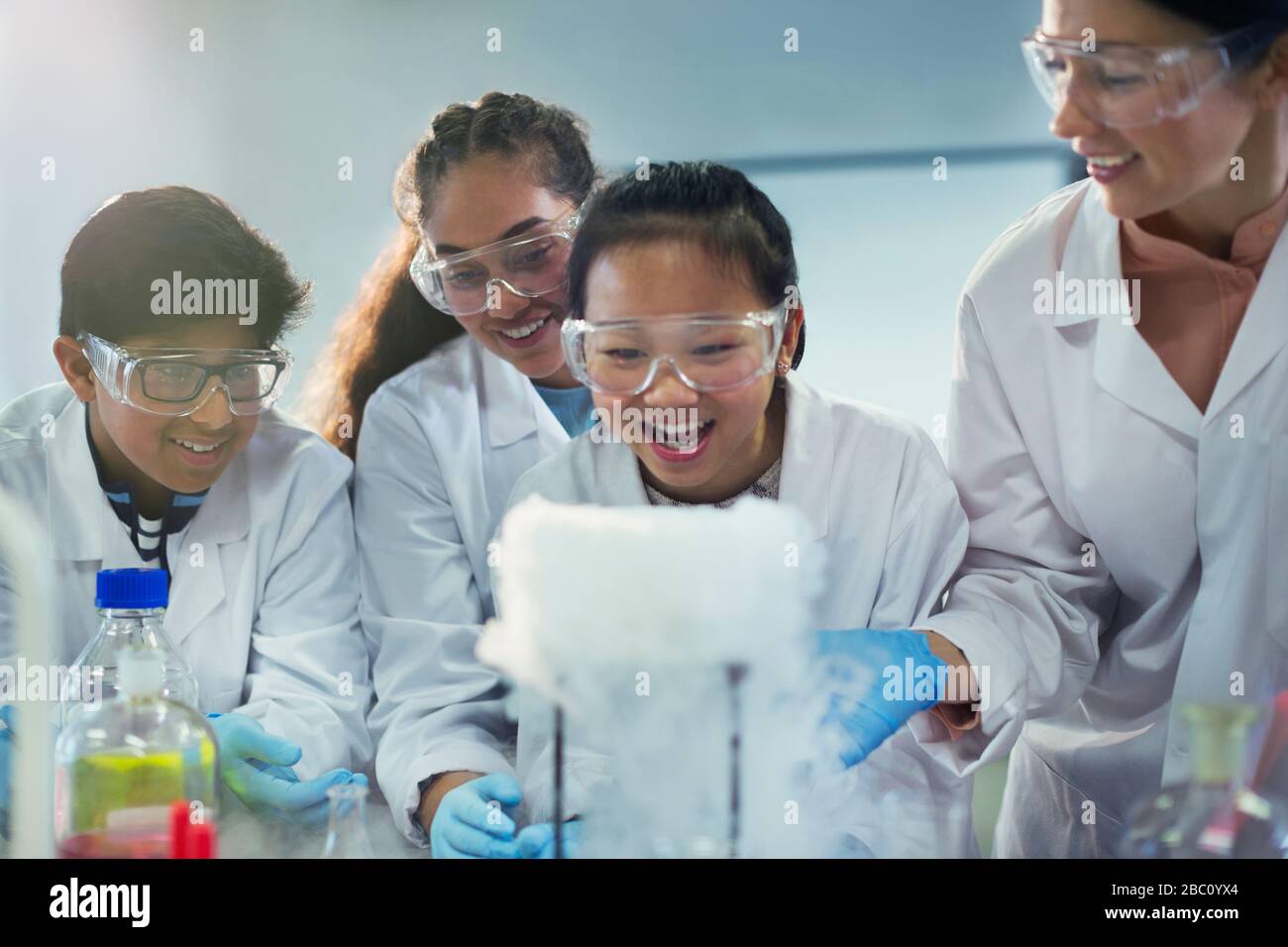 Neugierige, lächelnde Studenten beobachten chemische Reaktionen und führen wissenschaftliche Experimente im Laborunterricht durch Stockfoto