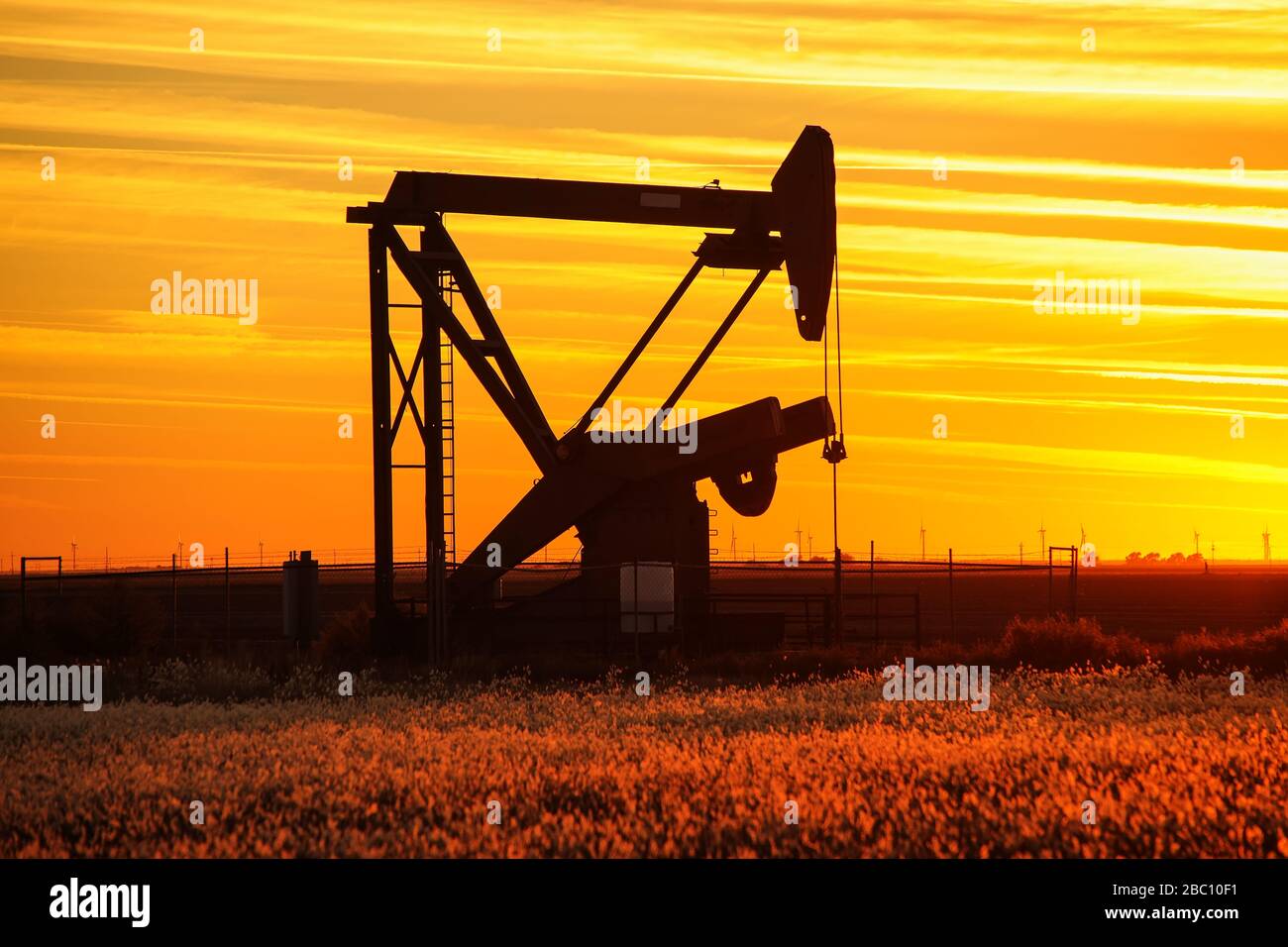 Silhouetted pumpjack im Ölfeld bei Sonnenuntergang Stockfoto