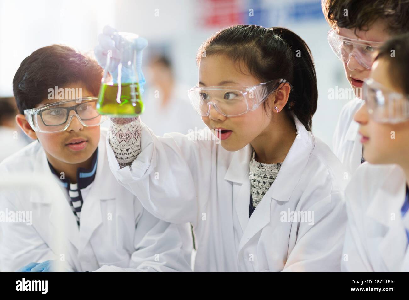 Neugierige Studenten untersuchen Flüssigkeit im Becher und führen wissenschaftliche Experimente im Laborunterricht durch Stockfoto