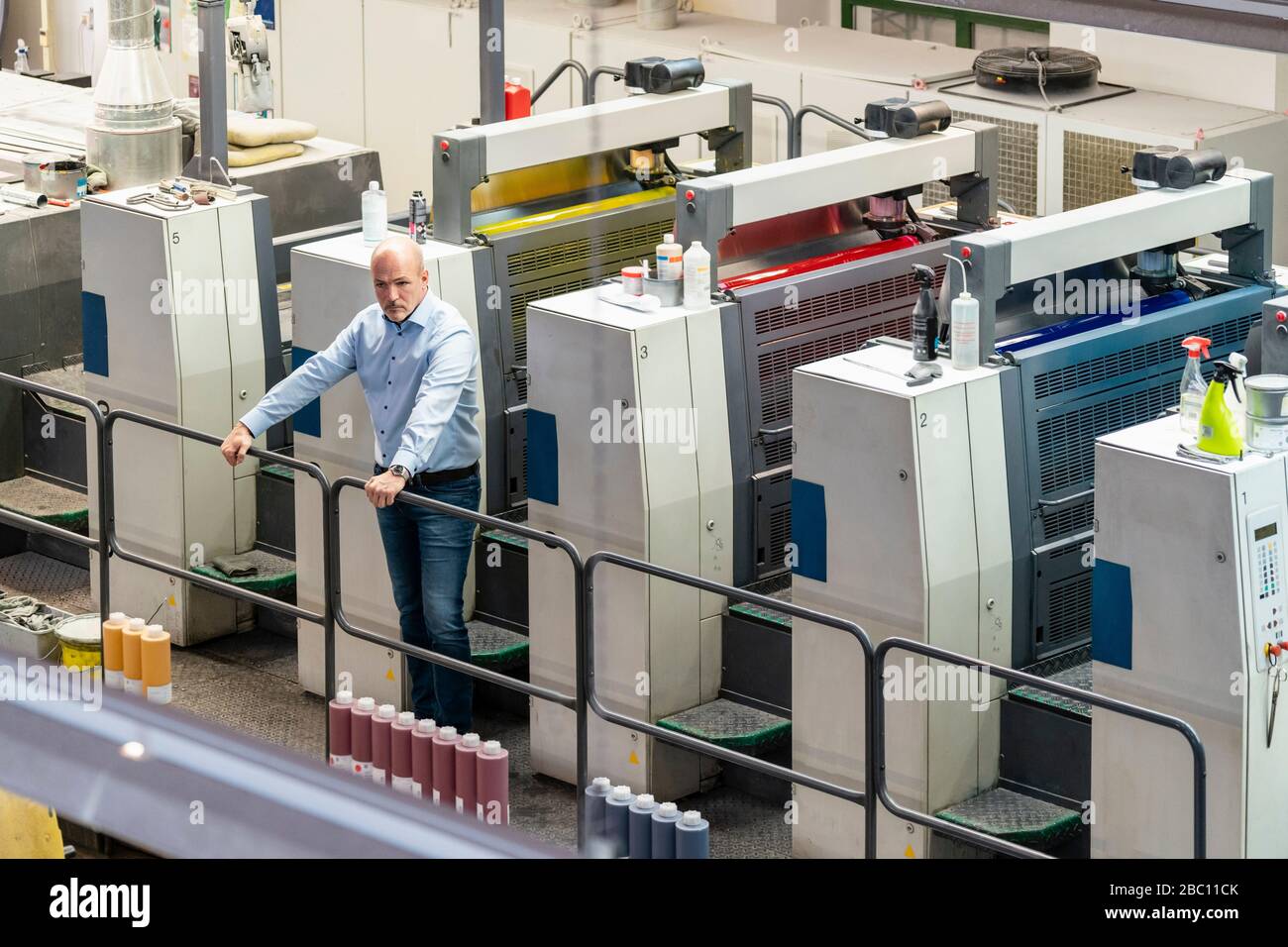 Geschäftsmann steht an Maschinen in einer Druckerei Stockfoto