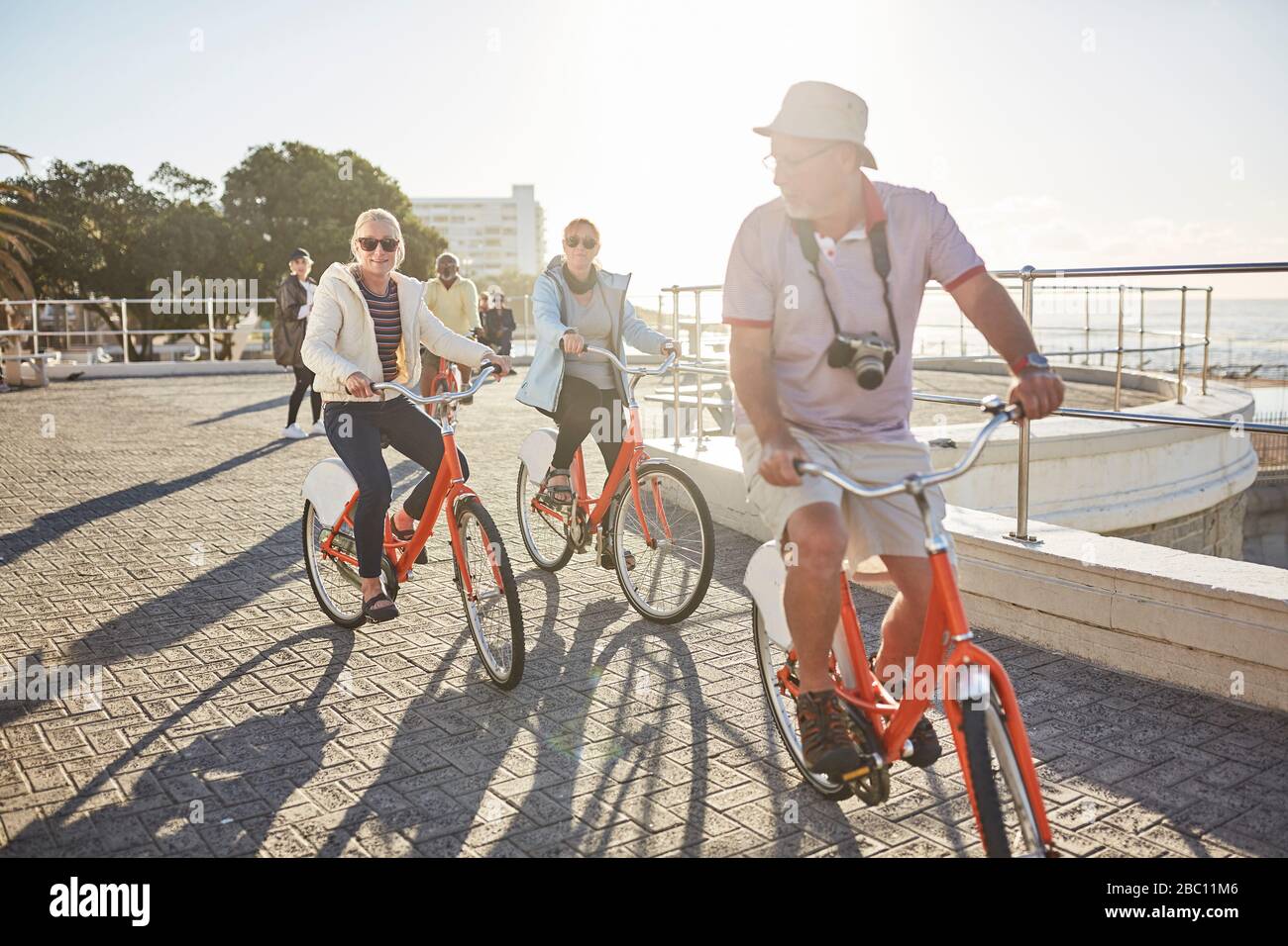 Aktive Senioren-Tourist-Freunde Fahrradfahren auf sonniger Strandpromenade Stockfoto